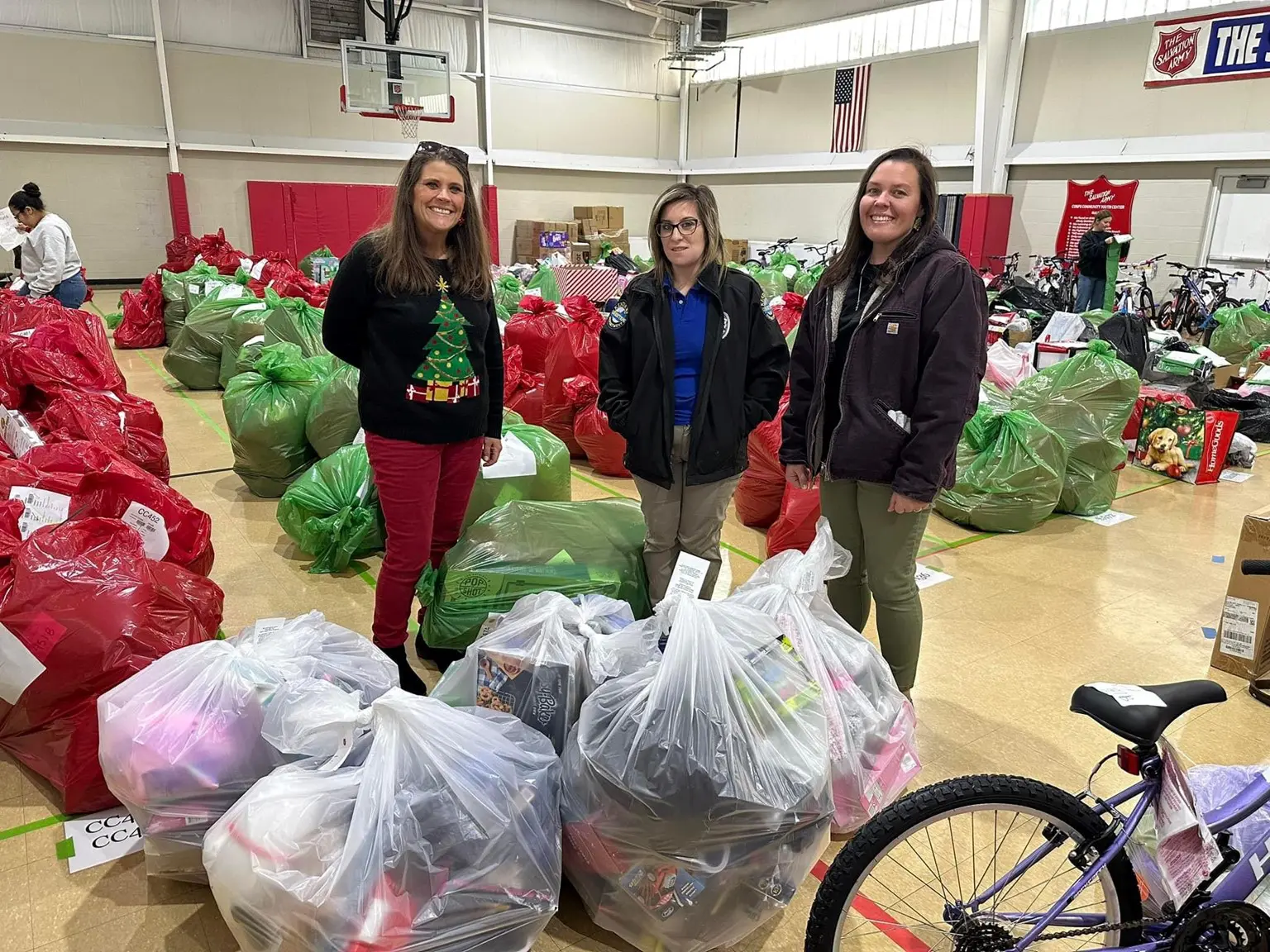 Three women standing in front of a pile of bags.